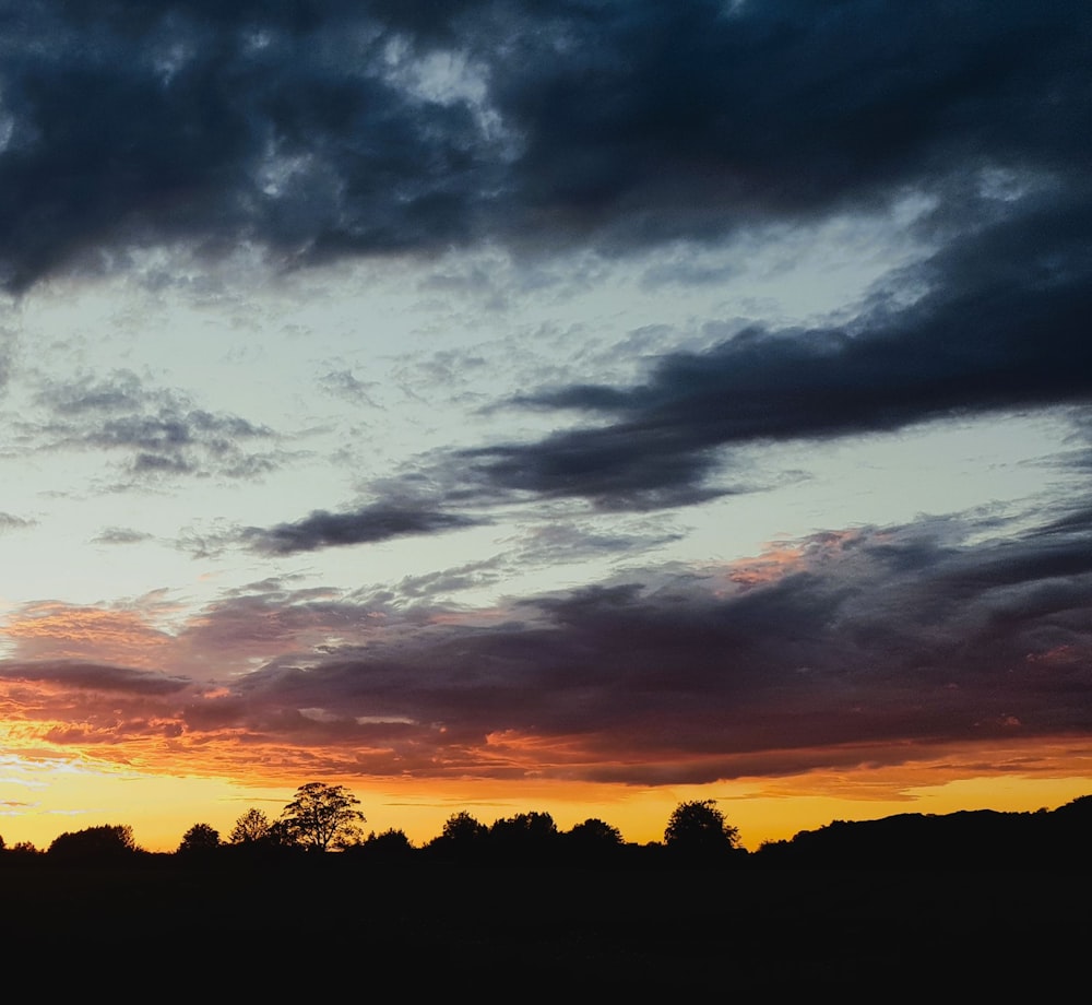 a plane flying through a cloudy sky at sunset