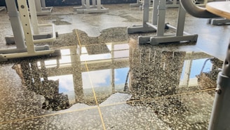 Janitors wiping desks and floors in a bright, modern school classroom.