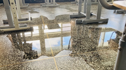 Janitors wiping desks and floors in a bright, modern school classroom.