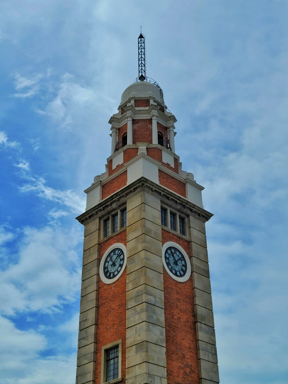 ein hoher gemauerter Glockenturm mit einer Uhr auf jeder Seite