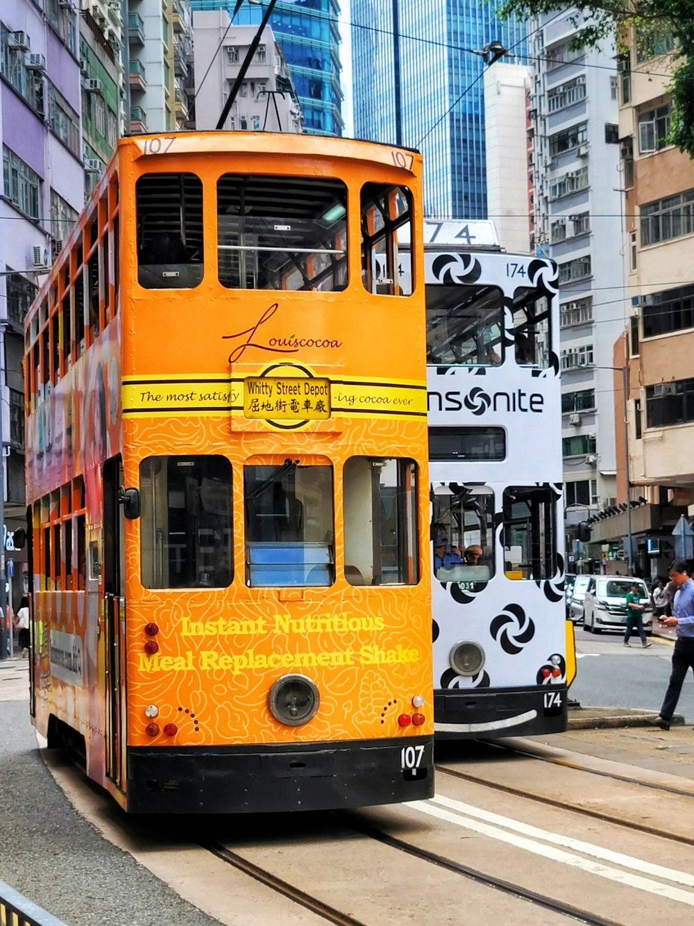 a double decker bus driving down a street next to tall buildings