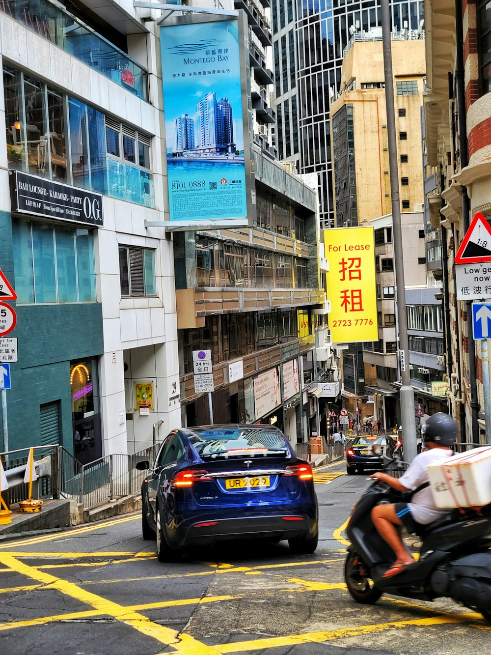 a man riding a motorcycle down a street next to tall buildings