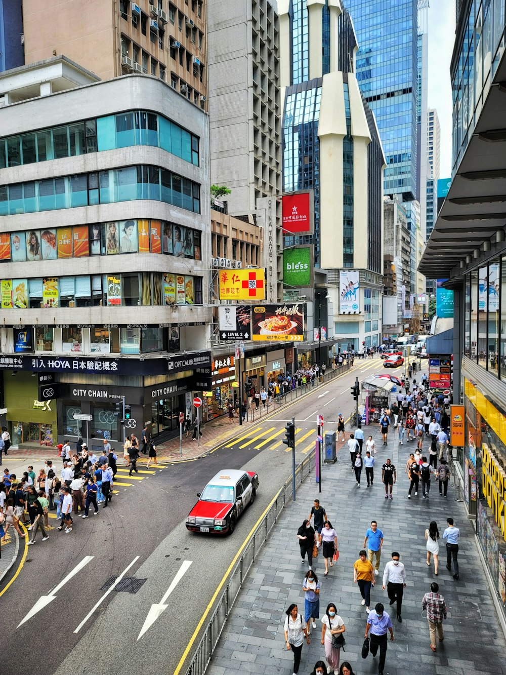 a group of people walking down a street next to tall buildings