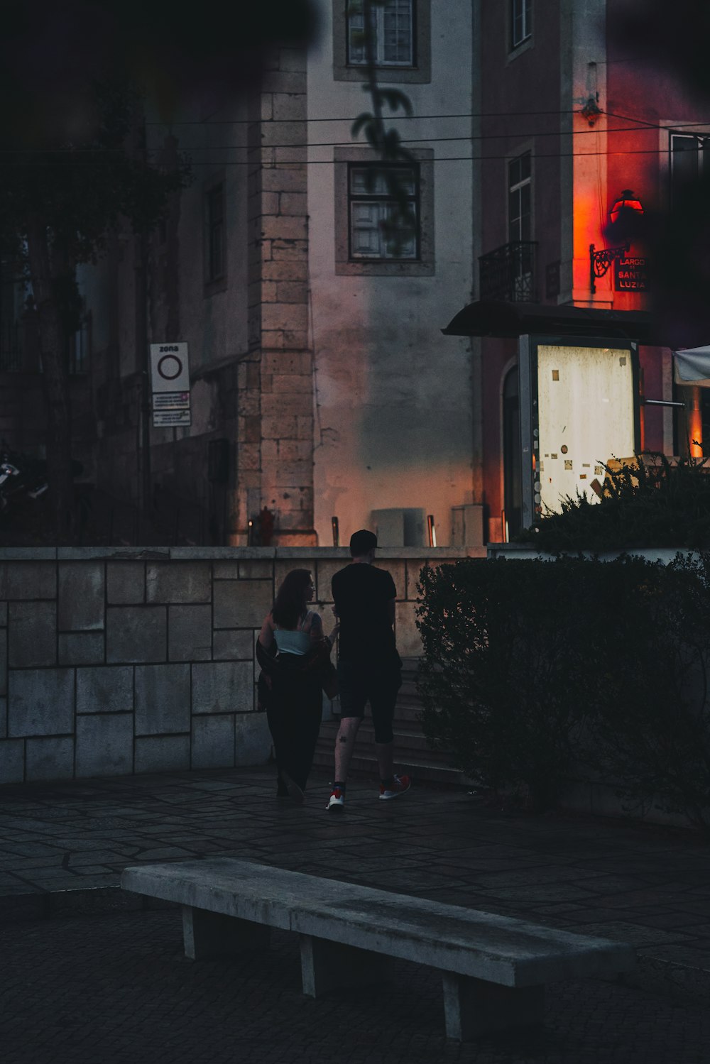 a man and a woman walking down a street at night