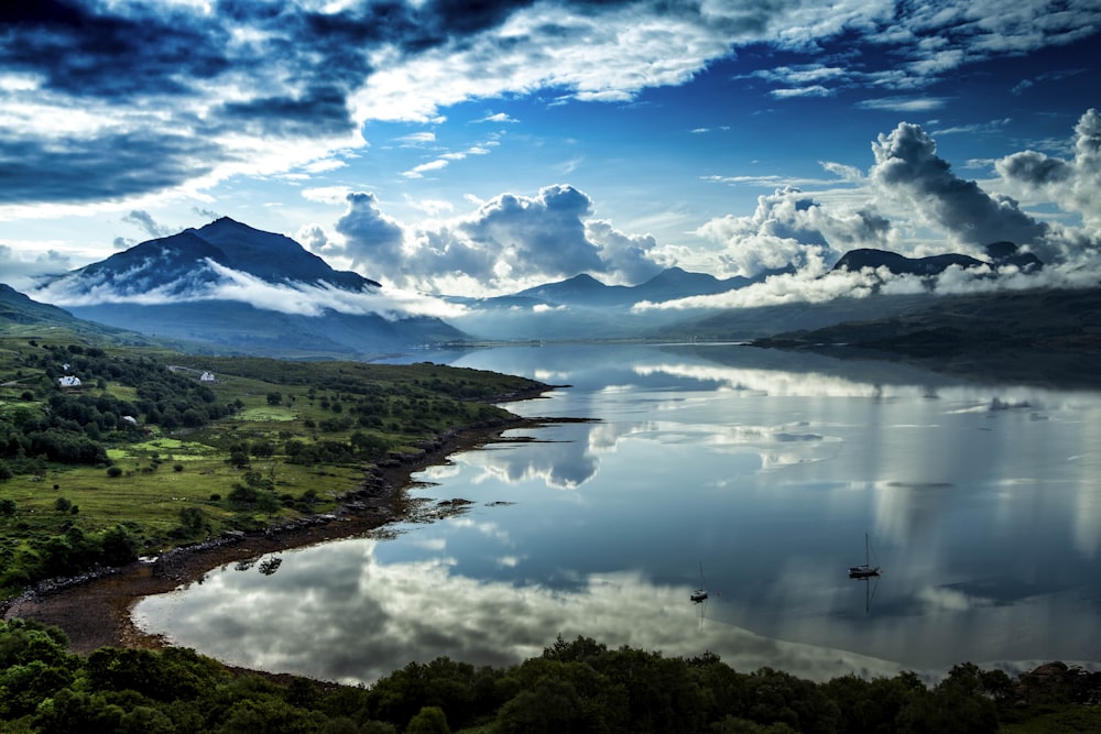 a lake surrounded by mountains under a cloudy sky