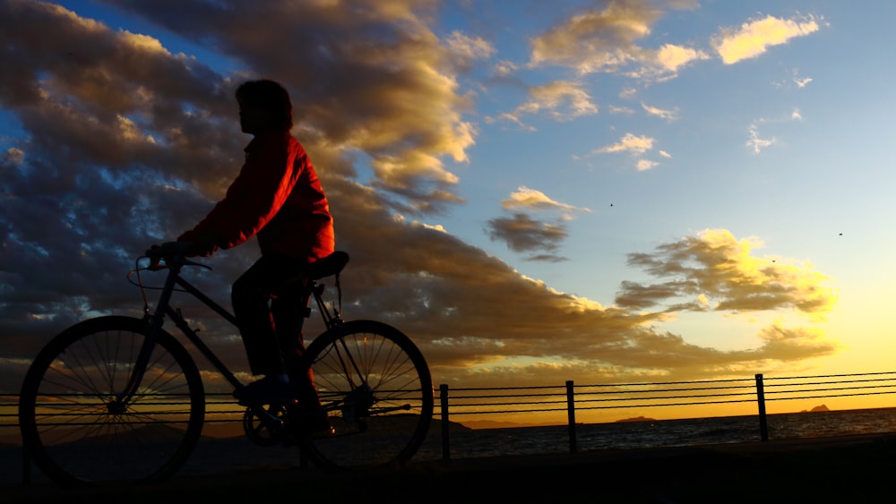 a man riding a bike down a street next to the ocean