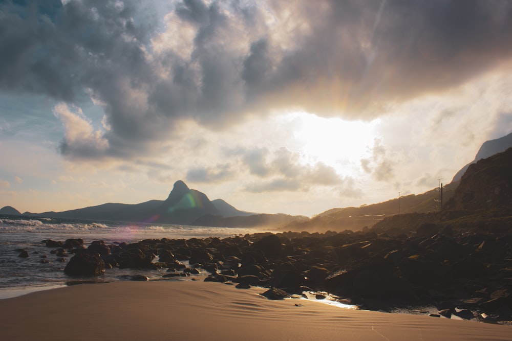 the sun is setting over a rocky beach