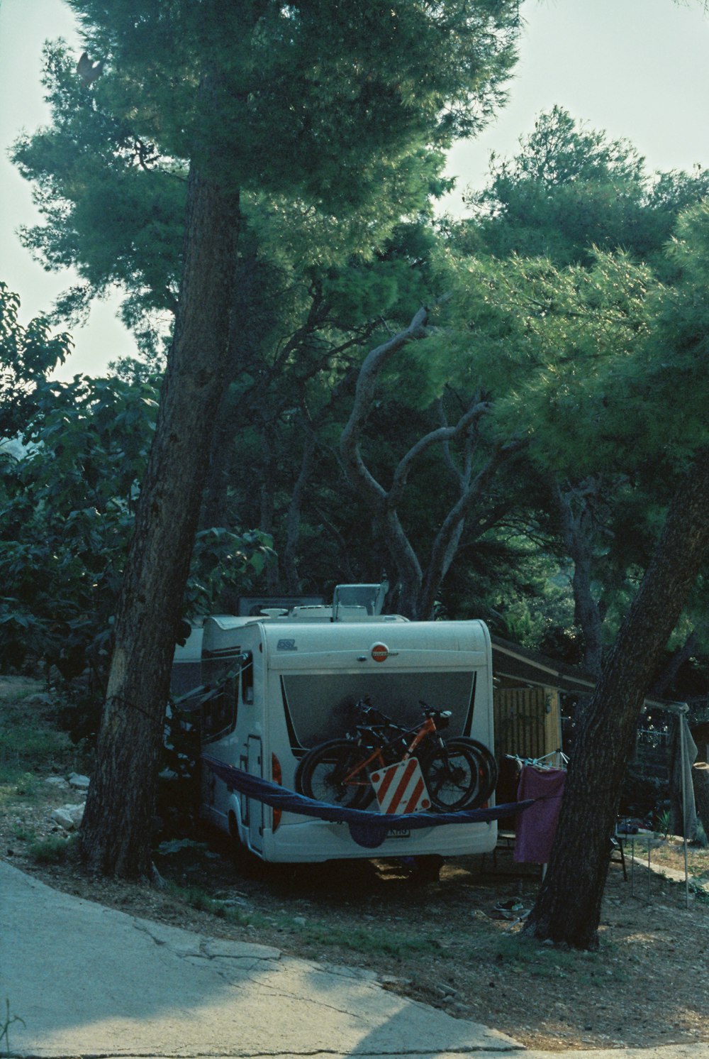 a camper parked in the shade of a tree