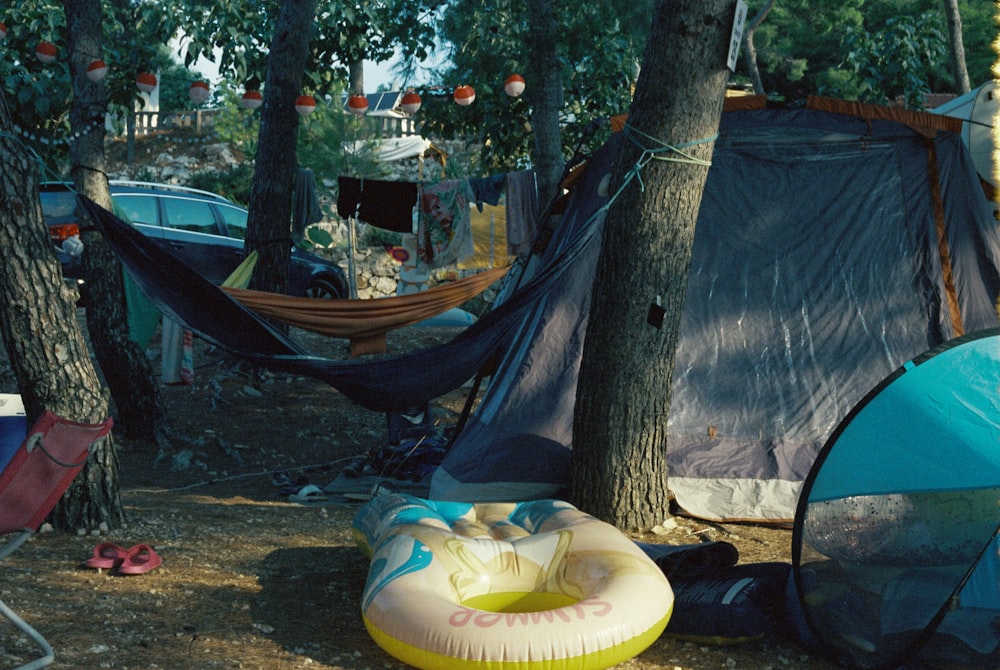 a group of tents and a hammock in the woods