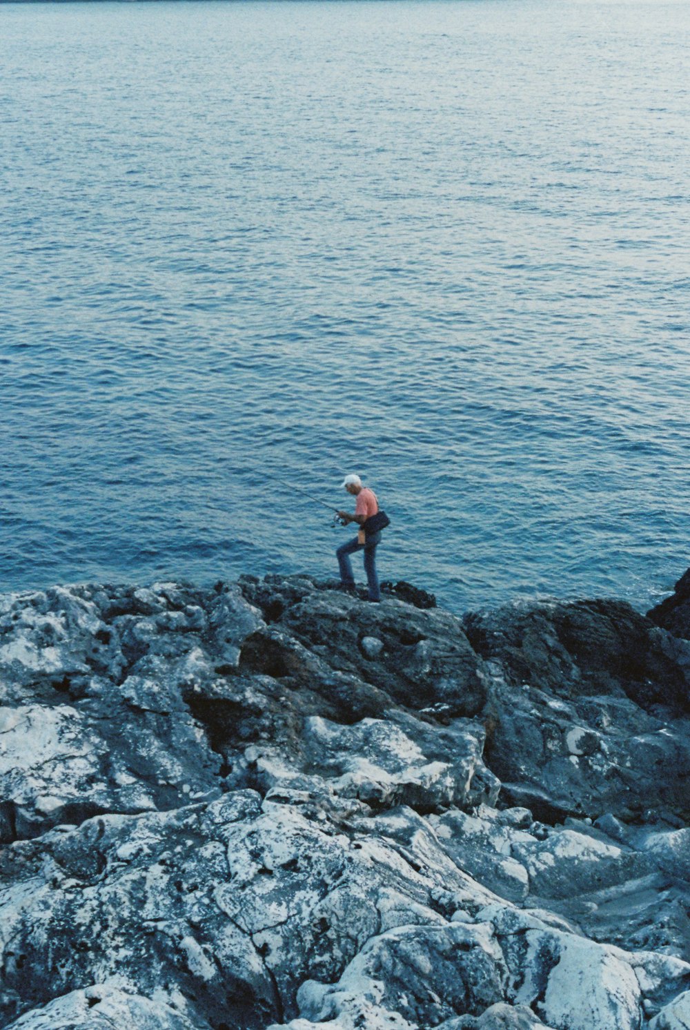 a man standing on top of a rocky cliff next to the ocean