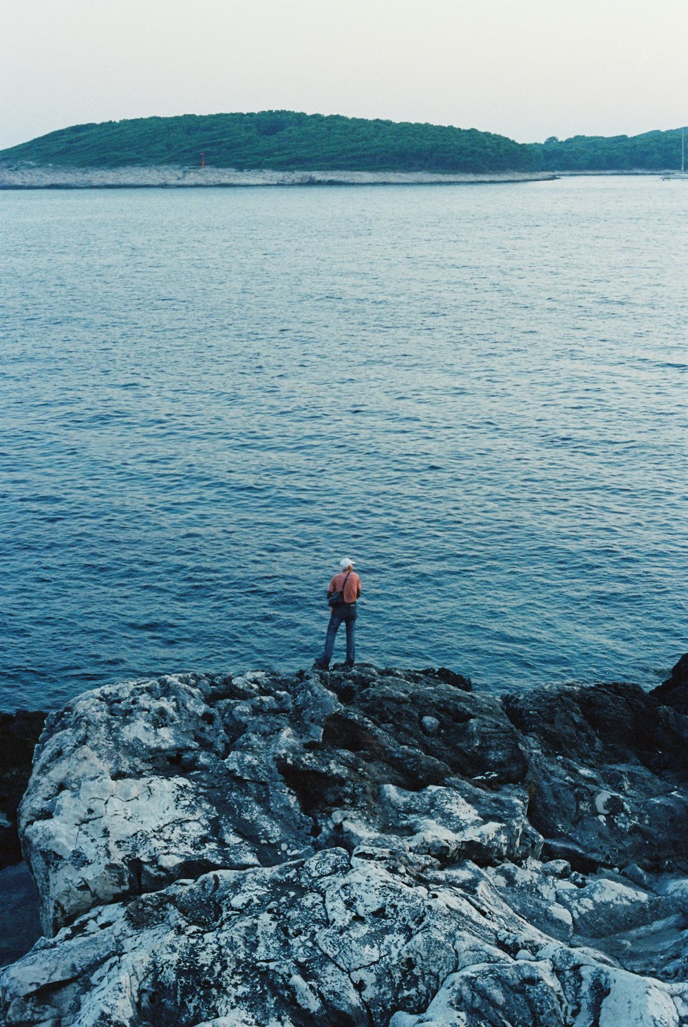 a man standing on top of a rock near the ocean