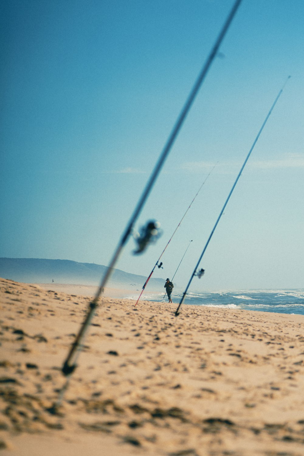 a couple of people on a beach with some fishing rods