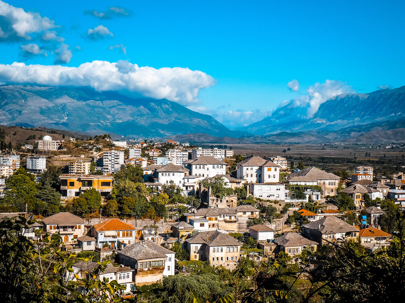 Gjirokastër’s stone roofs climbing the mountainside, with the valley beyond
