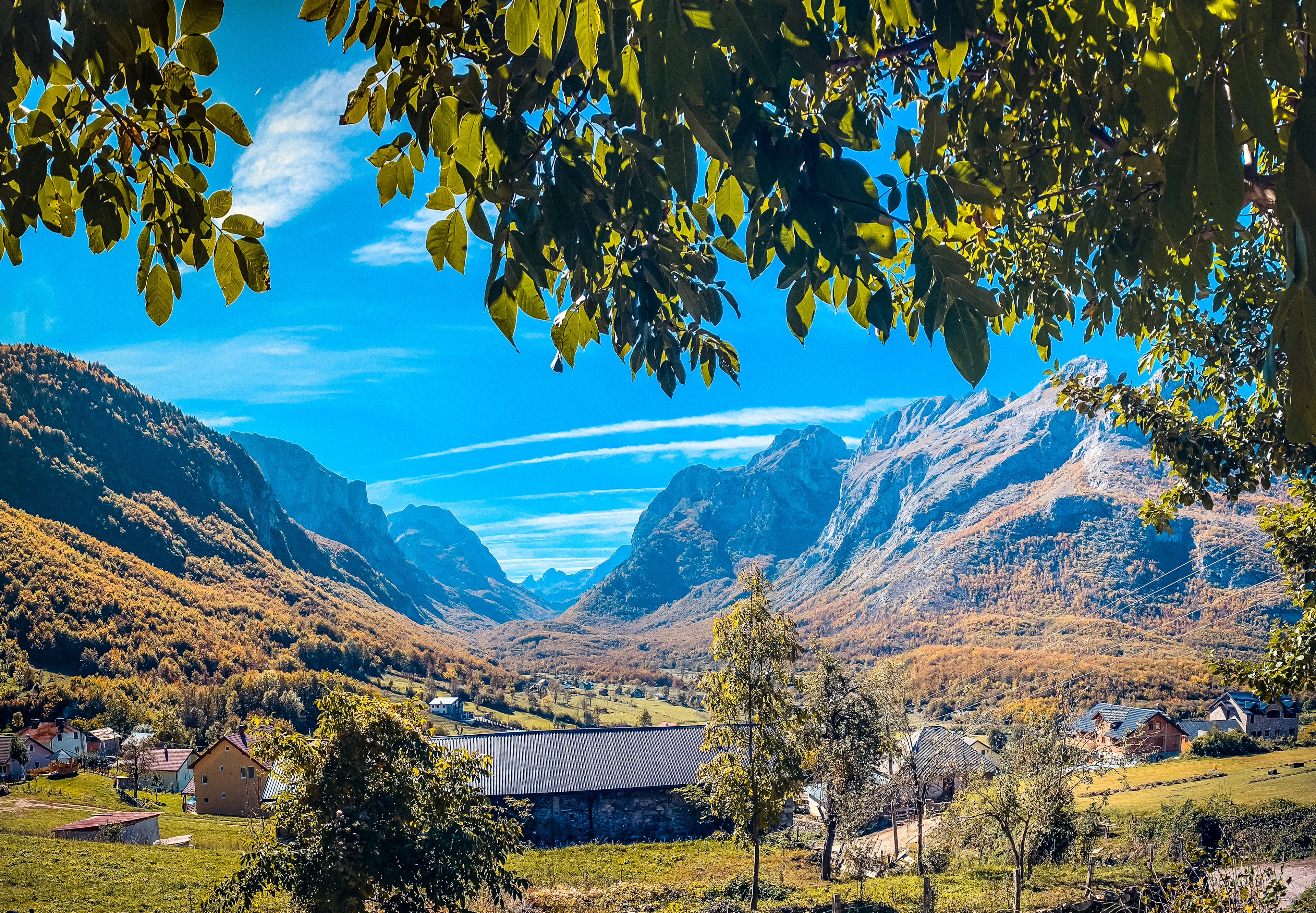 The houses of Vusanje among autumn trees beneath steep mountain walls, Montenegro