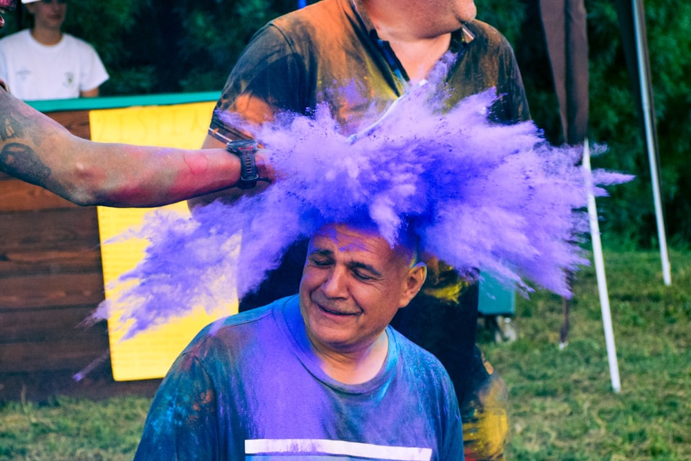 a man with a purple mohawk is getting his hair dyed purple