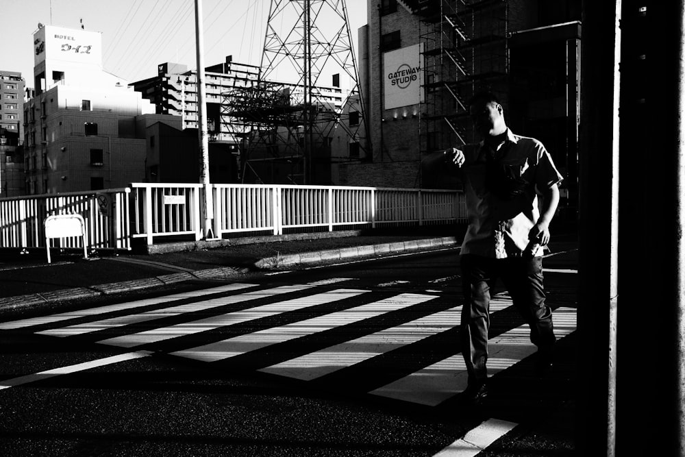 a man walking across a street next to tall buildings