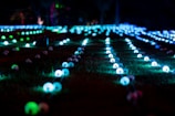 An outdoor night scene showing a cluster of uniquely designed glowcraft bottles lighting a garden party.