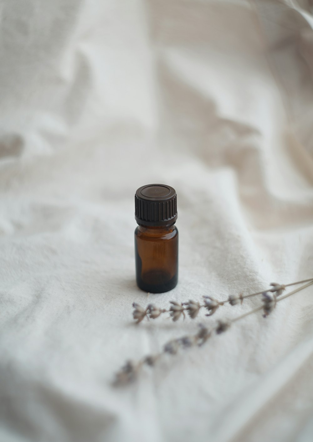 a bottle of essential oils sitting on a white sheet