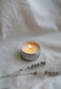 a white candle sitting on top of a white sheet