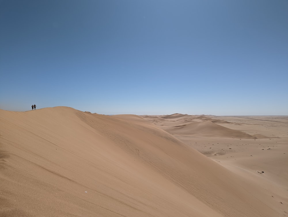 uma pessoa em pé no topo de uma duna de areia