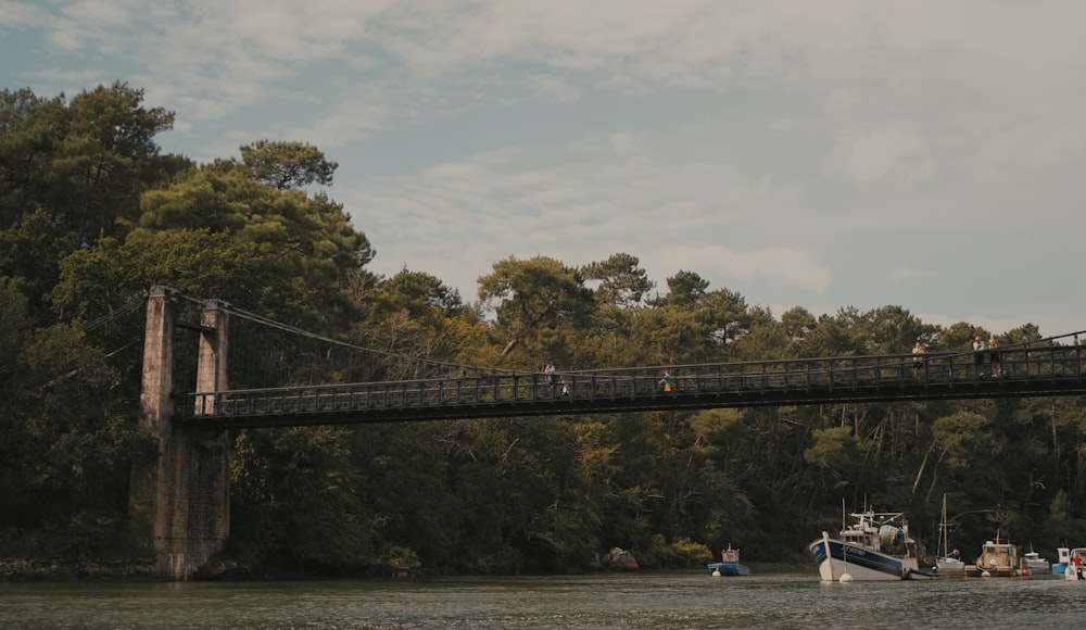 a group of boats floating on top of a river under a bridge