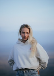 a woman with blonde hair wearing a white hoodie