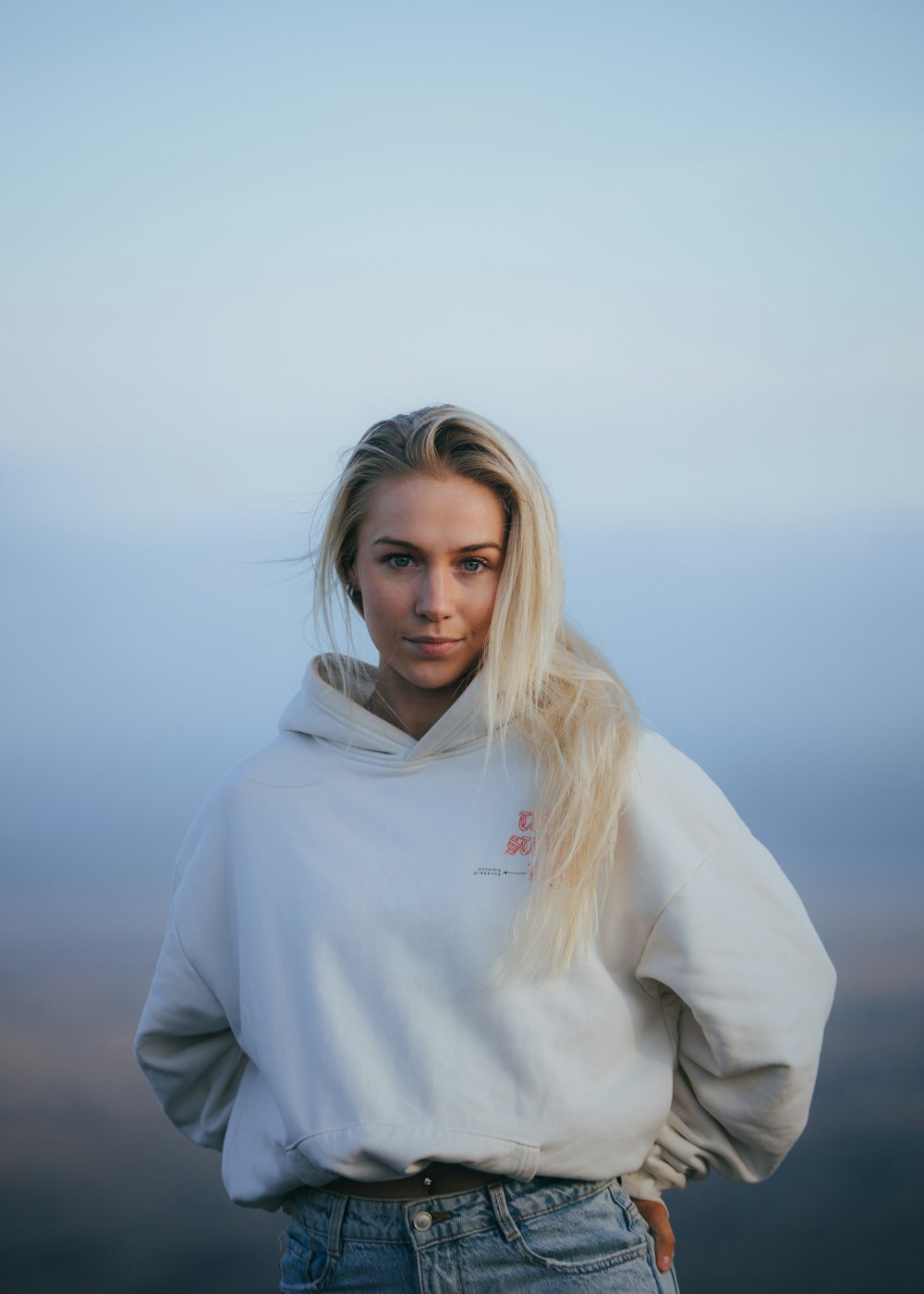 a woman with blonde hair wearing a white hoodie