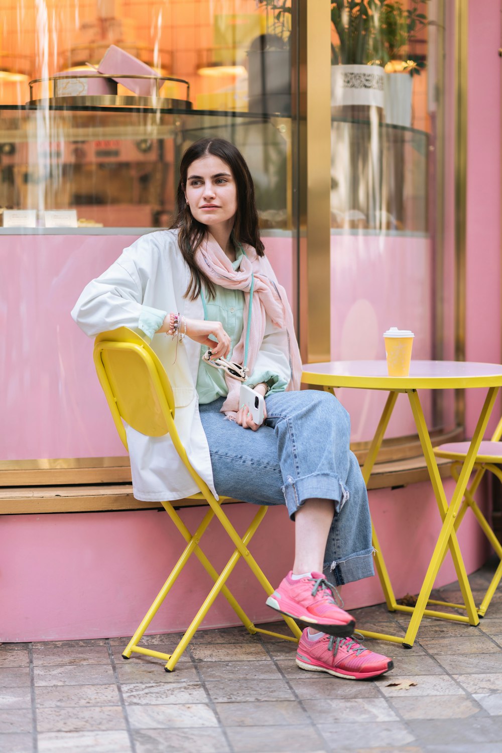 a woman sitting on a yellow chair in front of a pink building