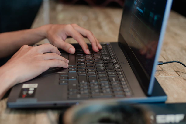 Close-up of hands typing on a laptop with home security content on screen.