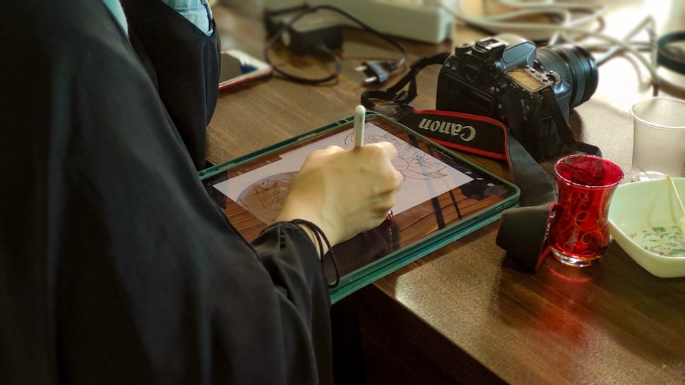 a person sitting at a desk writing on a tablet