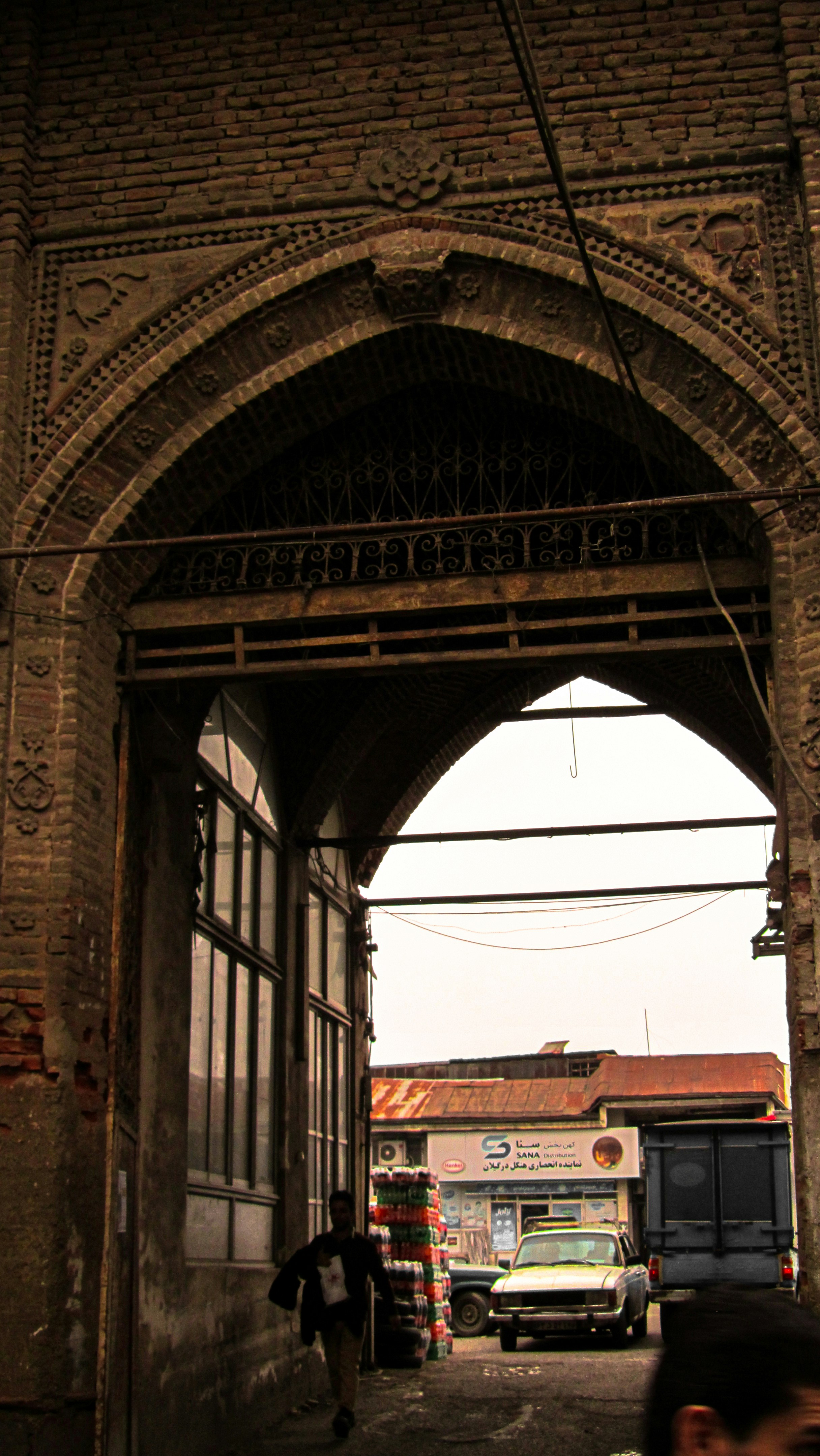 Un hombre caminando por una calle bajo un arco