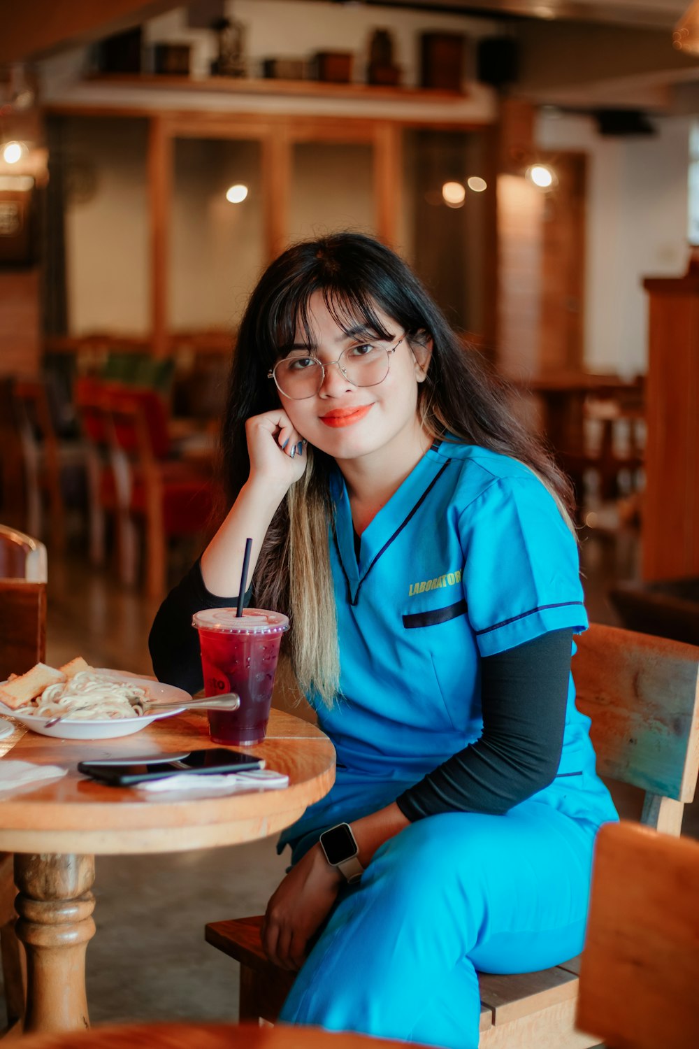 a woman sitting at a table with a drink