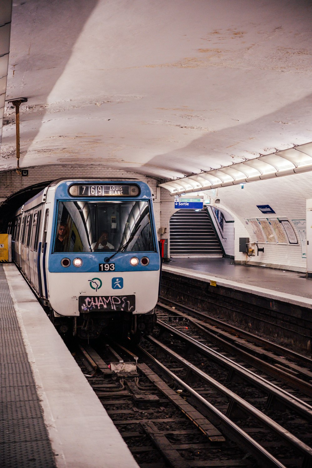 a blue and white train pulling into a train station