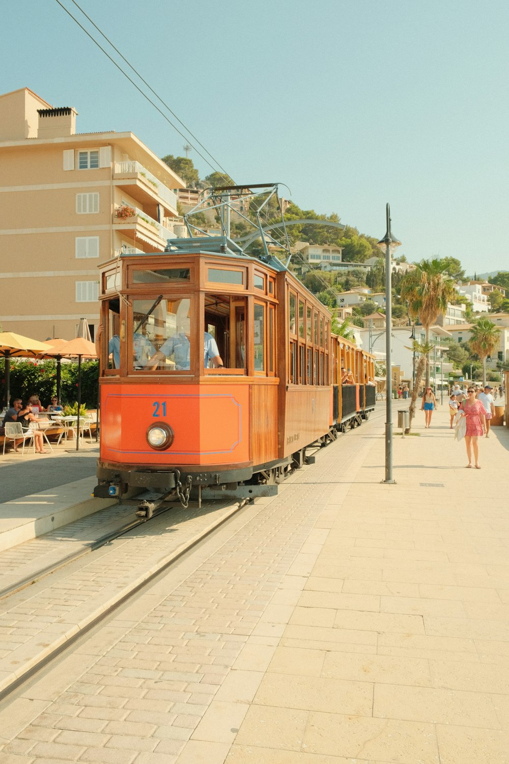 an orange trolley car traveling down a street next to a tall building