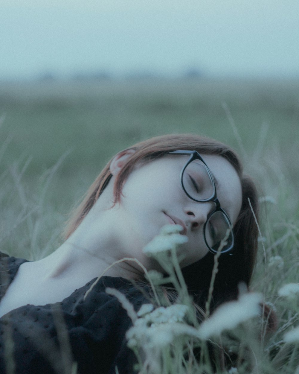 a woman laying in a field with her eyes closed