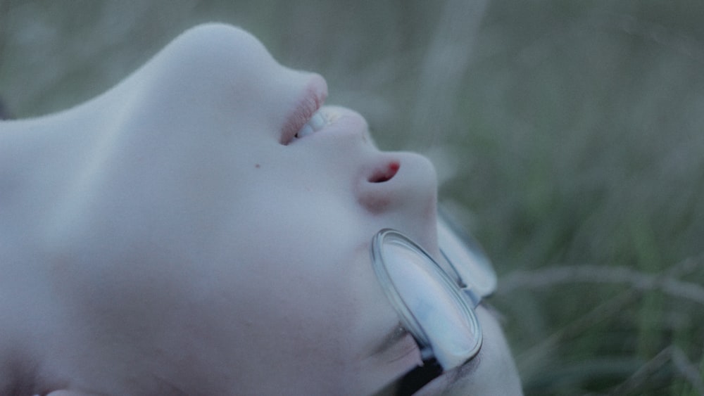 a woman laying in the grass with a magnifying glass