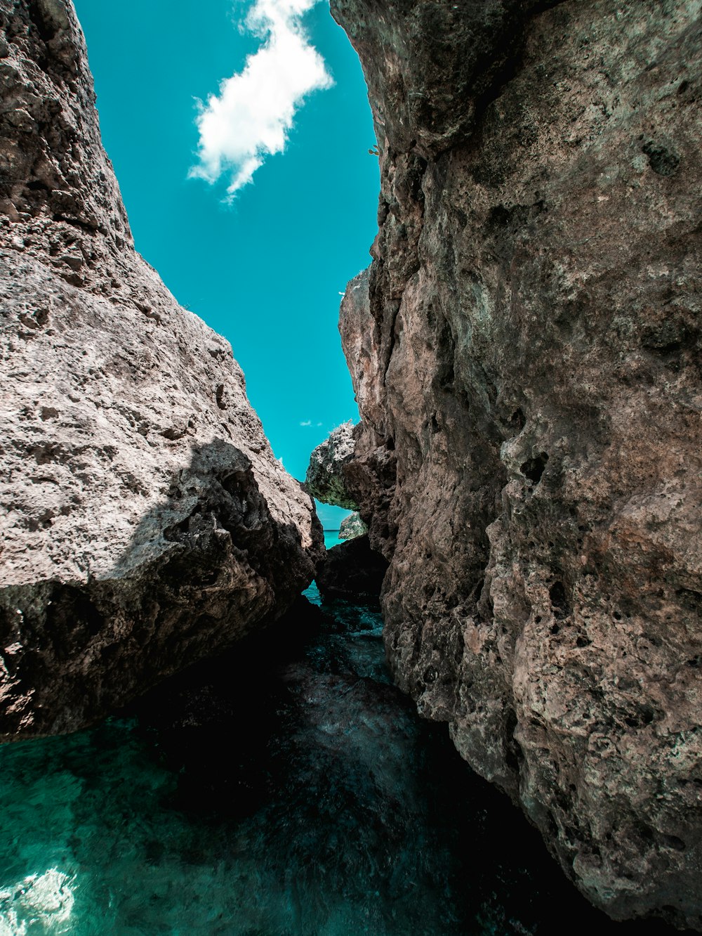 uma pessoa em pé sobre uma rocha ao lado de um corpo de água
