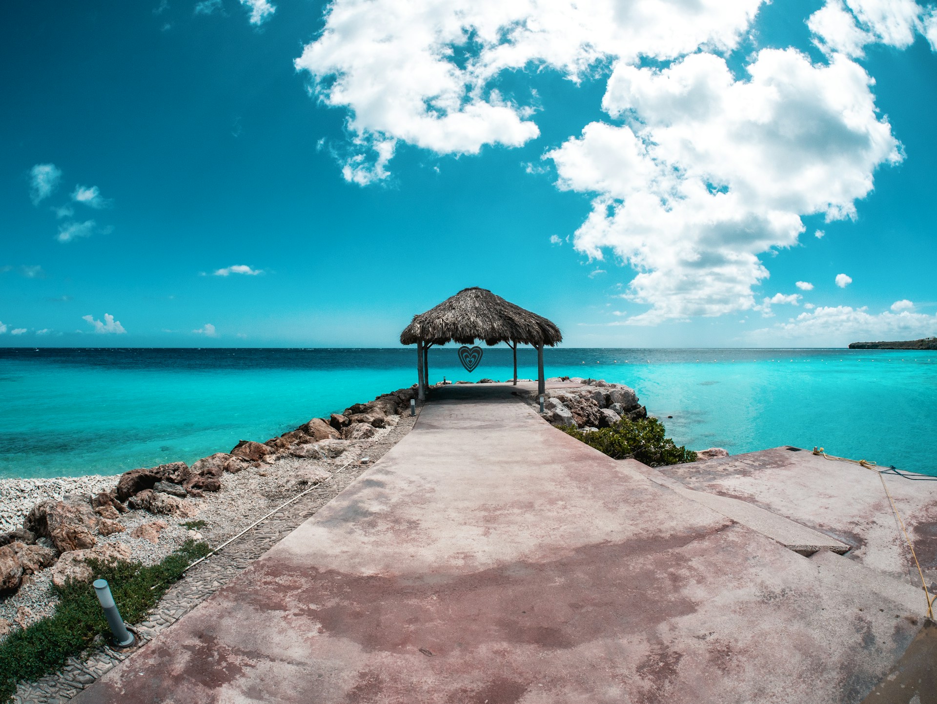 a pier with a thatched roof over the ocean