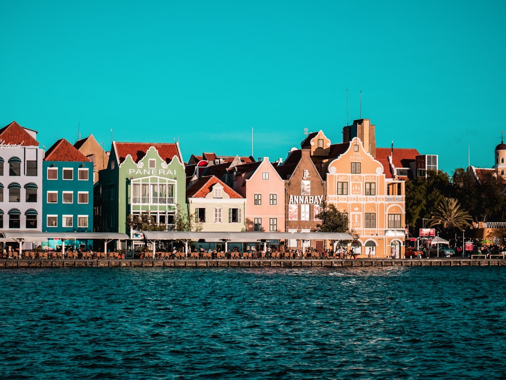 a row of colorful houses sitting on the shore of a body of water