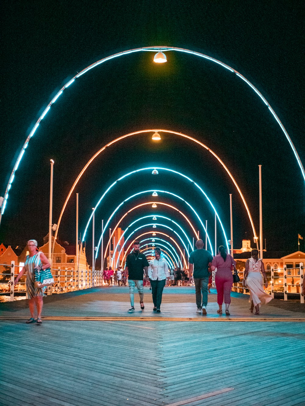 a group of people walking down a walkway at night