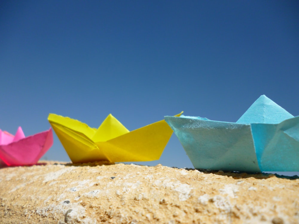 three origami boats sitting on top of a rock