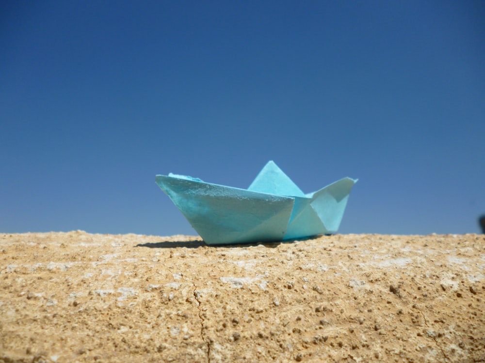 a paper boat sitting on top of a sandy beach