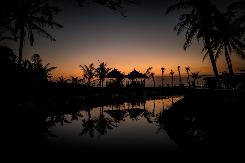 a sunset with palm trees and a gazebo