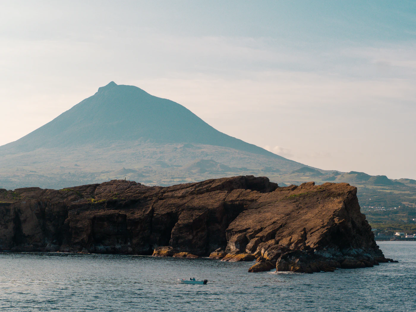 Mount Pico rising behind a rocky headland and sea in the Azores