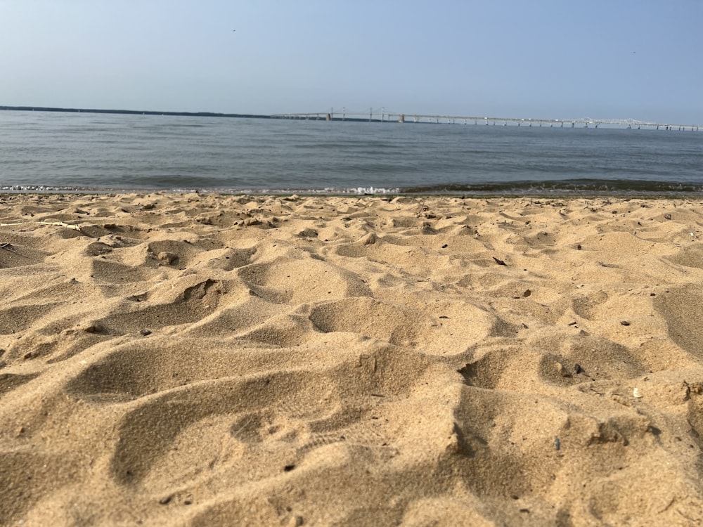 Una playa de arena con un cuerpo de agua en el fondo