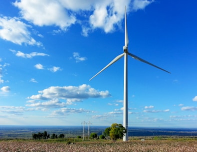 A wind turbine spinning in a green field with a bright horizon.