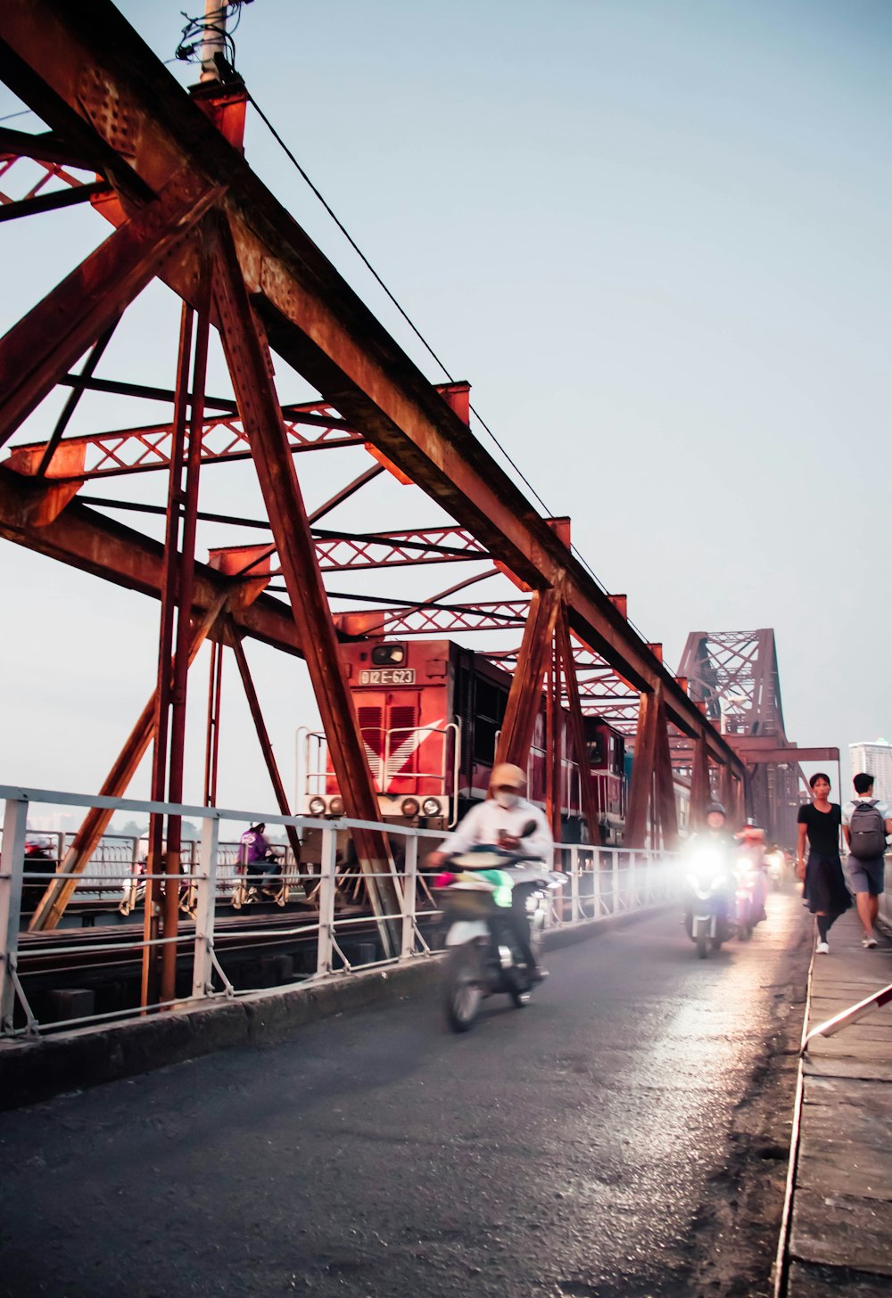 a man riding a motorcycle down a street next to a bridge