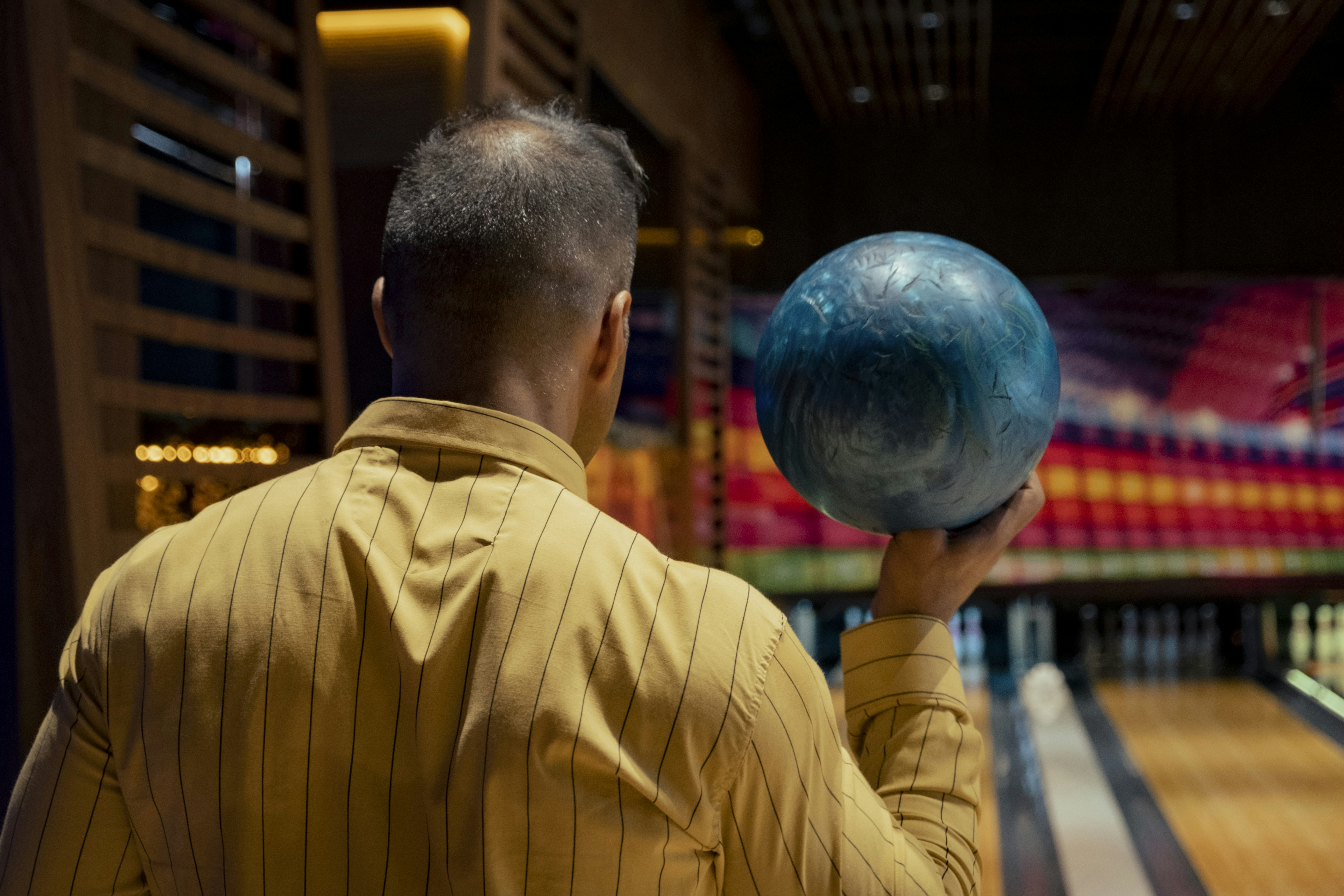 a man holding a bowling ball in front of a bowling alley