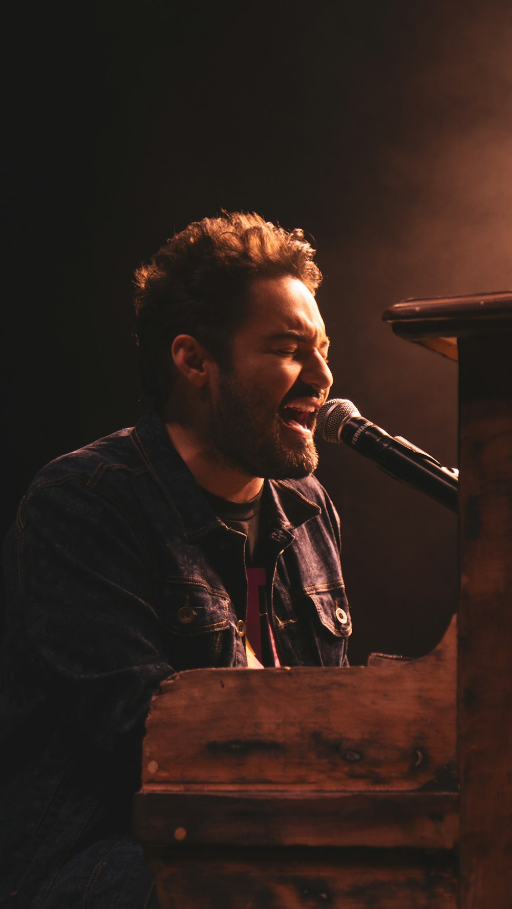 a man singing into a microphone while sitting at a piano