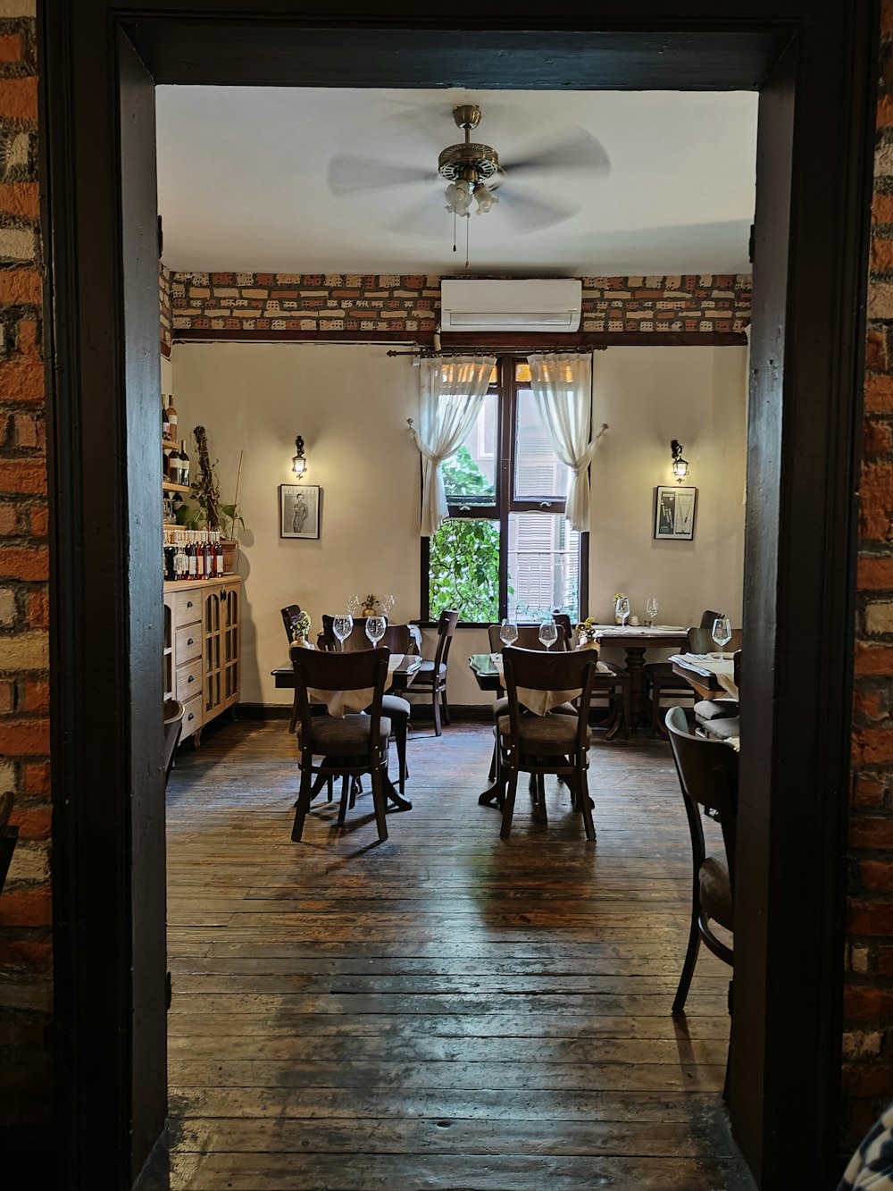 a dining room with wooden floors and a brick wall